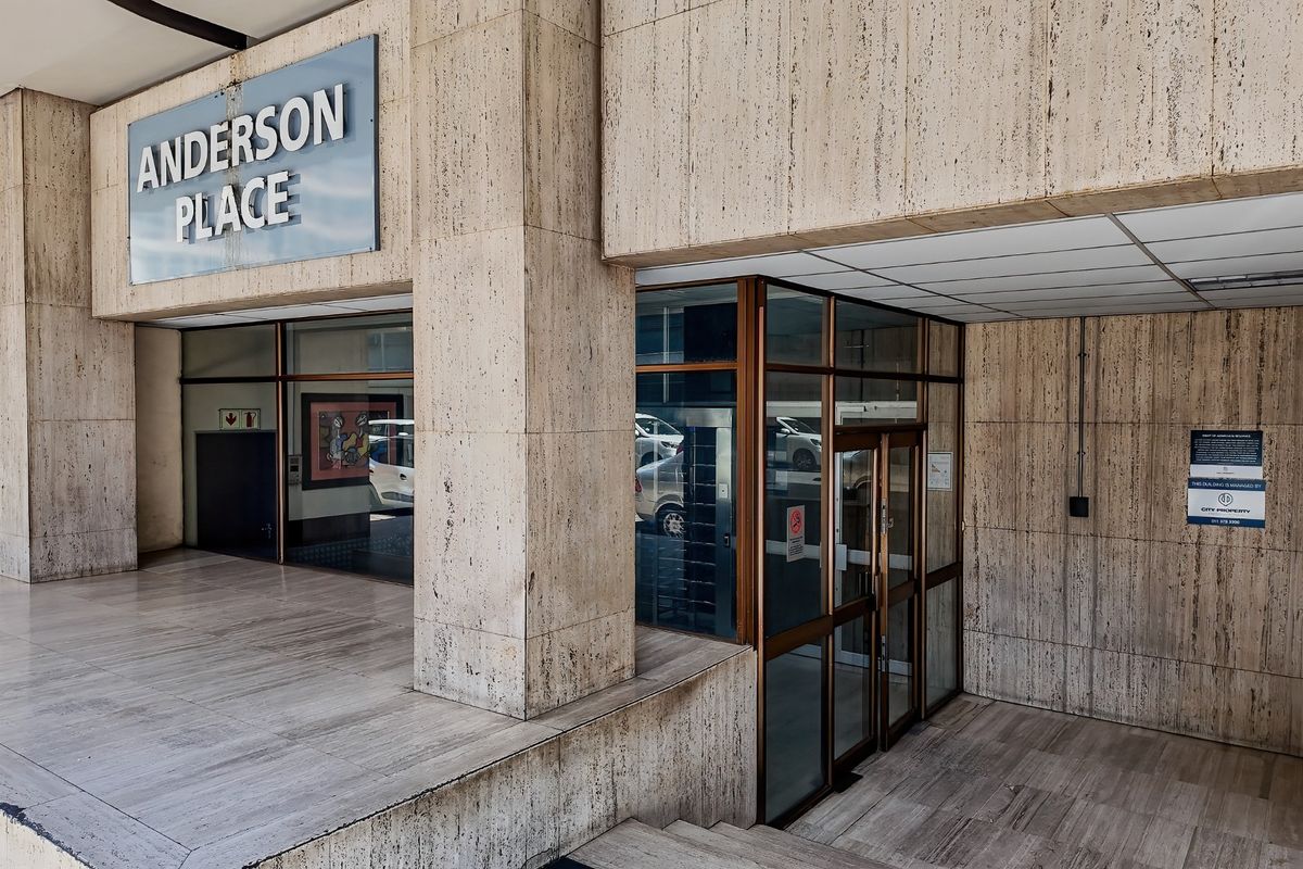 Main entrance area of Anderson Place featuring travertine stone cladding, glass doors, and tiled flooring.