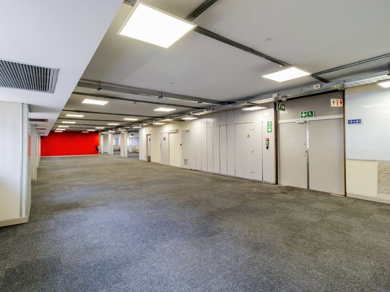 A spacious, open-plan commercial office area featuring carpeted flooring, recessed LED lighting, ducted air conditioning, and integrated storage units.