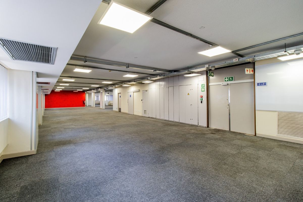 A spacious, open-plan commercial office area featuring carpeted flooring, recessed LED lighting, ducted air conditioning, and integrated storage units.