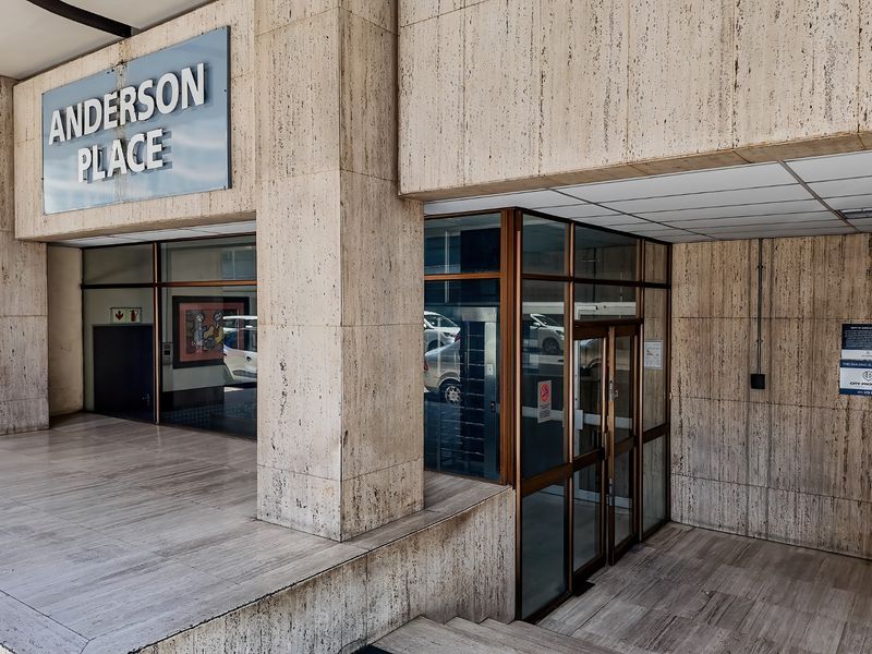Main entrance area of Anderson Place featuring travertine stone cladding, glass doors, and tiled flooring.