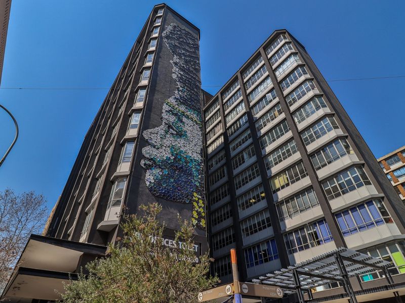 A low-angle view of a multi-story commercial building featuring a prominent artistic mural on the facade and modern window configurations.