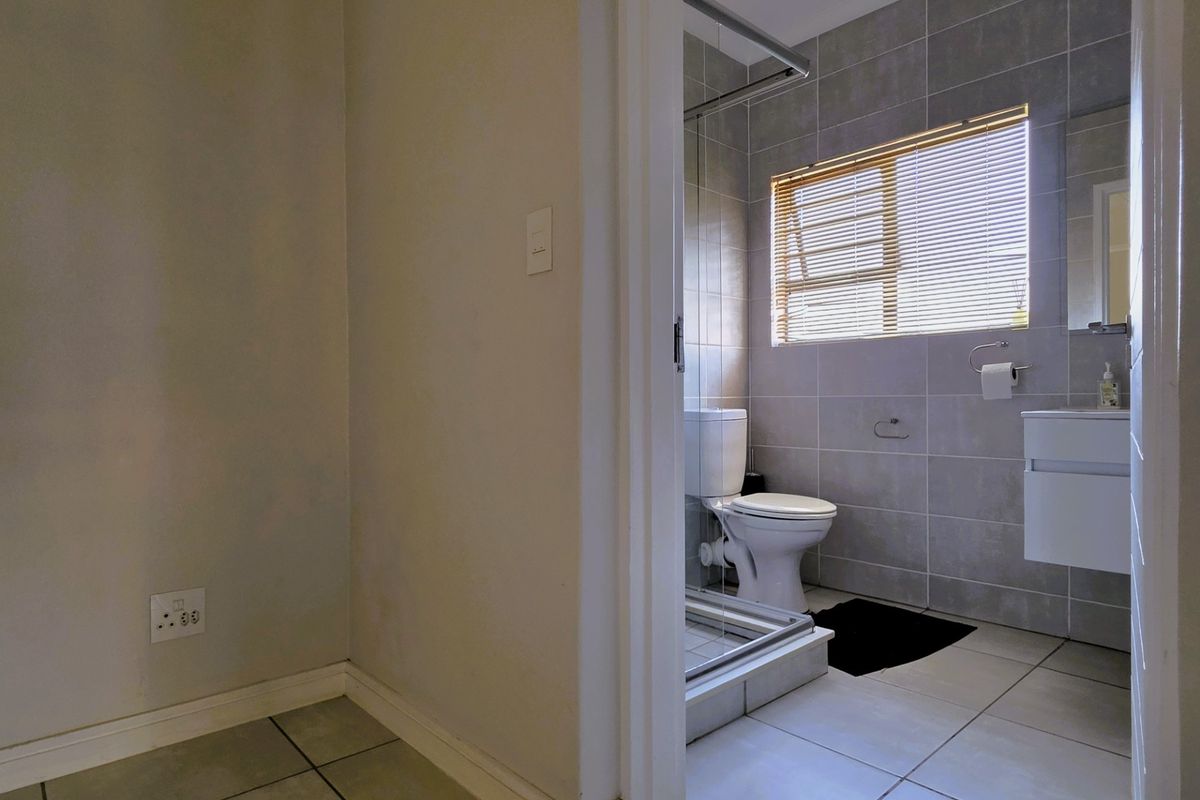 A clean, modern bathroom featuring tiled walls and flooring, a wall-mounted vanity, and a glass-enclosed shower area.