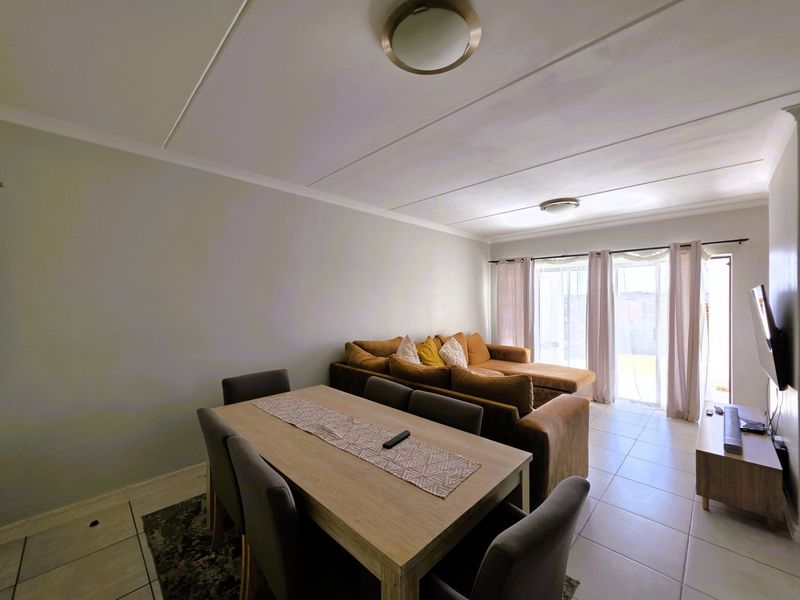 Open plan living and dining area featuring tiled flooring, coved ceilings, and a sliding glass door providing access to the exterior.