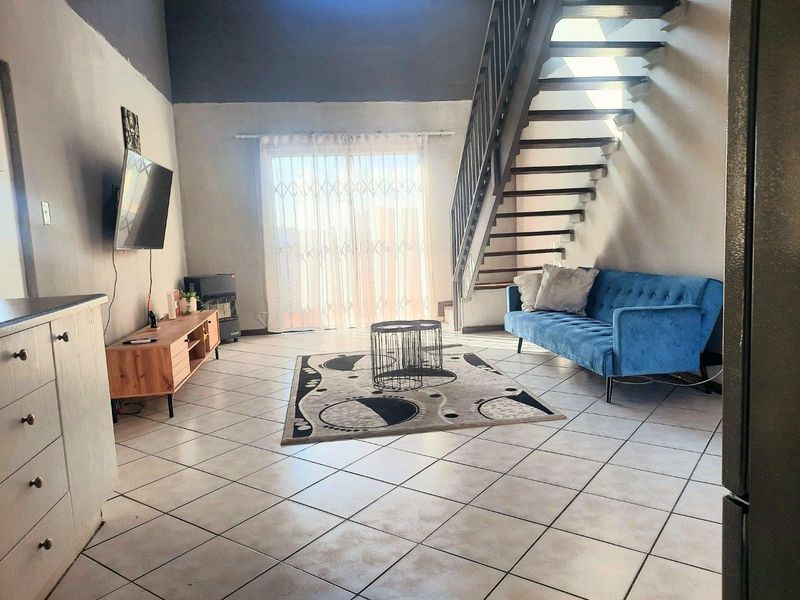 Open-plan living area featuring tiled flooring, a staircase leading to the upper level, and a sliding glass door providing access to the exterior.