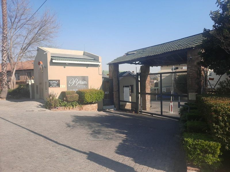The entrance to Bellairs Brooke apartment complex featuring a secure gated access point, guard house, and paved driveway.