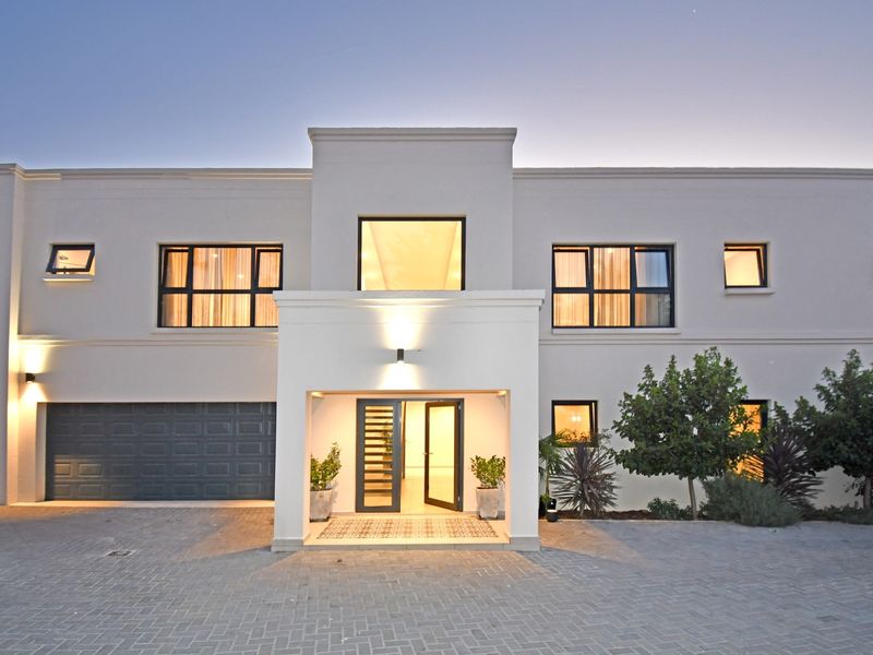 A modern double-story residence featuring a paved driveway, double garage, and a welcoming covered entrance with decorative tiling.