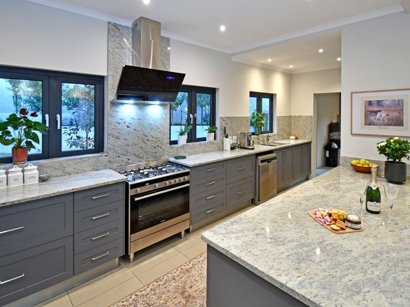 Modern kitchen featuring high-quality granite countertops, shaker-style cabinetry, a gas stove with extractor fan, and a spacious central island.