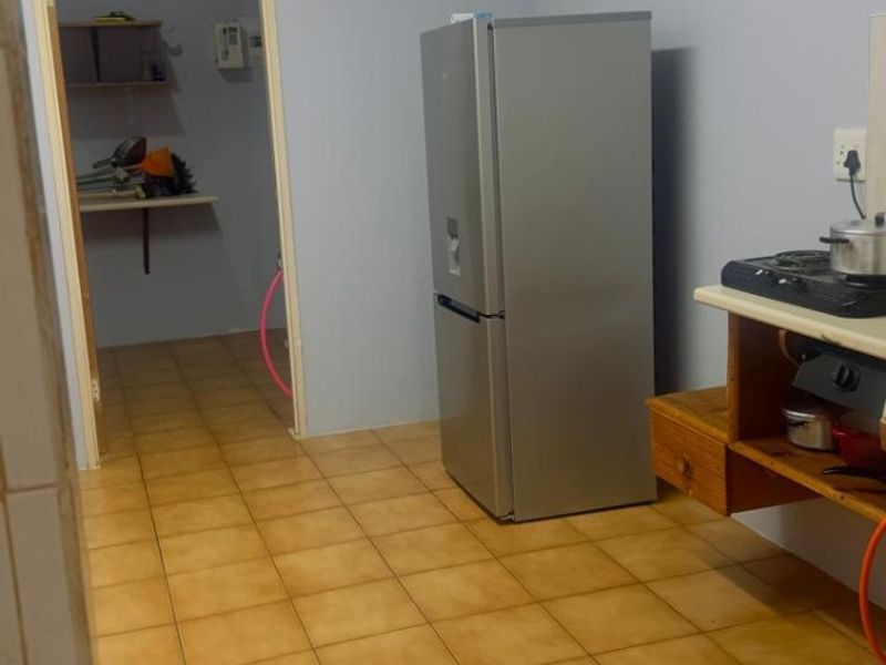 A functional kitchen area featuring tiled flooring and built-in shelving, with an adjacent utility space visible through the doorway.