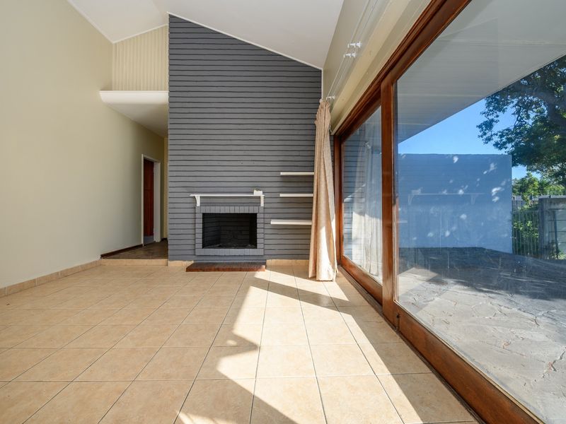 Spacious living area featuring a vaulted ceiling, a central fireplace with a grey feature wall, and large sliding glass doors opening to the exterior.