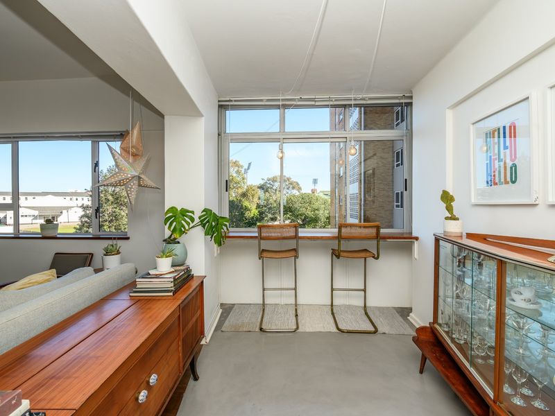 A bright living area featuring polished concrete floors, large windows with a built-in ledge, and an open-plan layout with natural light.