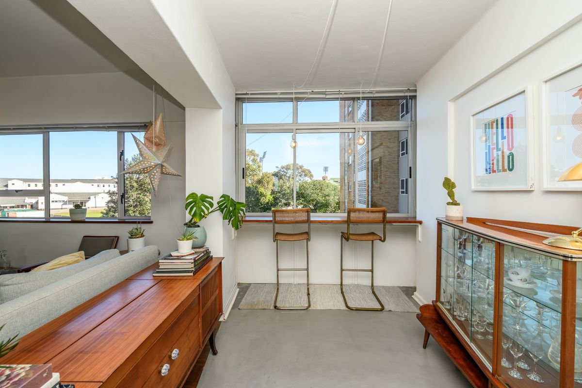 A bright living area featuring polished concrete floors, large windows with a built-in ledge, and an open-plan layout with natural light.