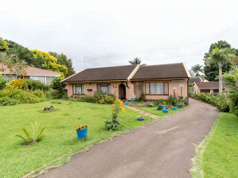 Front view of a single-story residential house featuring a tiled roof, an asphalt driveway, and a spacious front garden.