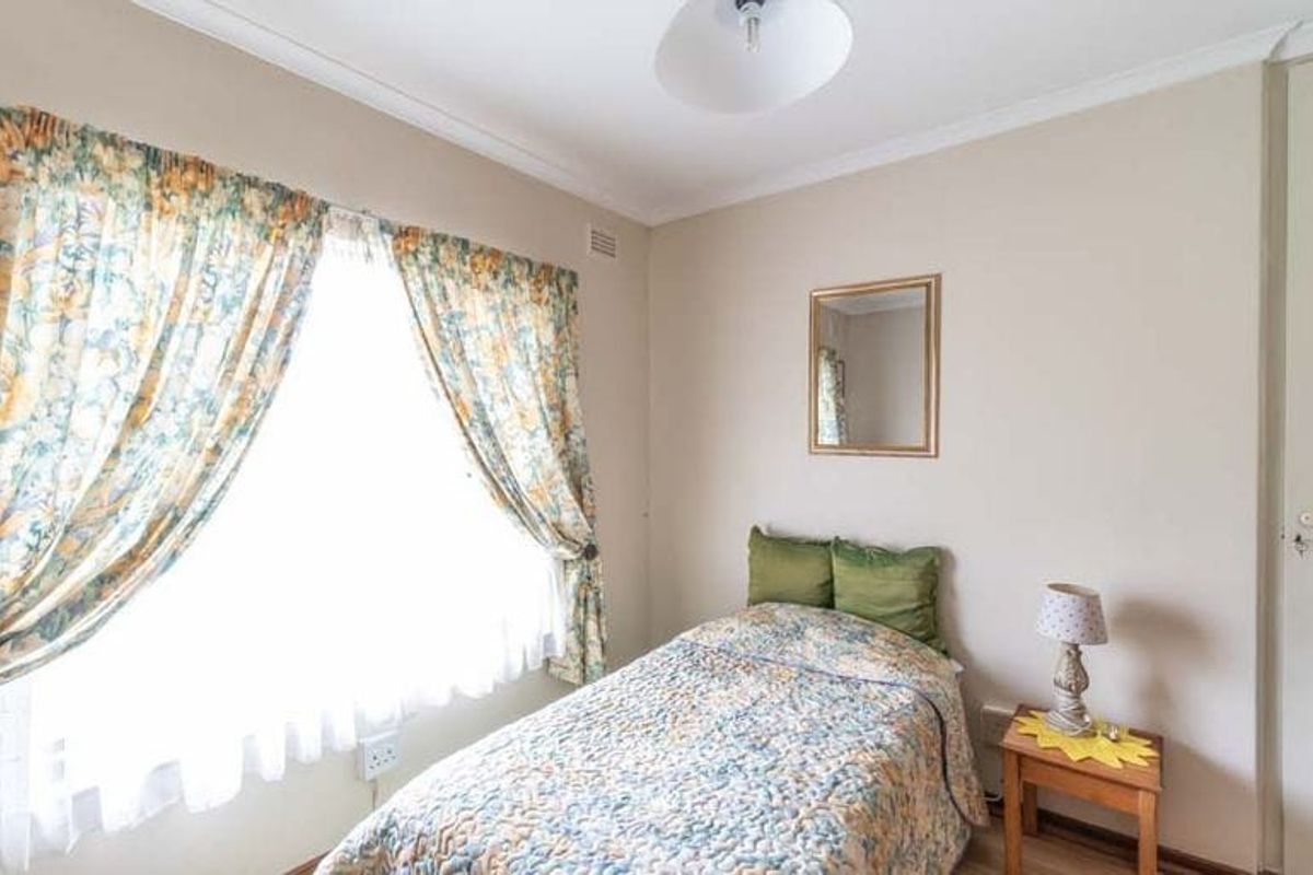 A neutrally painted bedroom featuring coving and a large window with natural light.