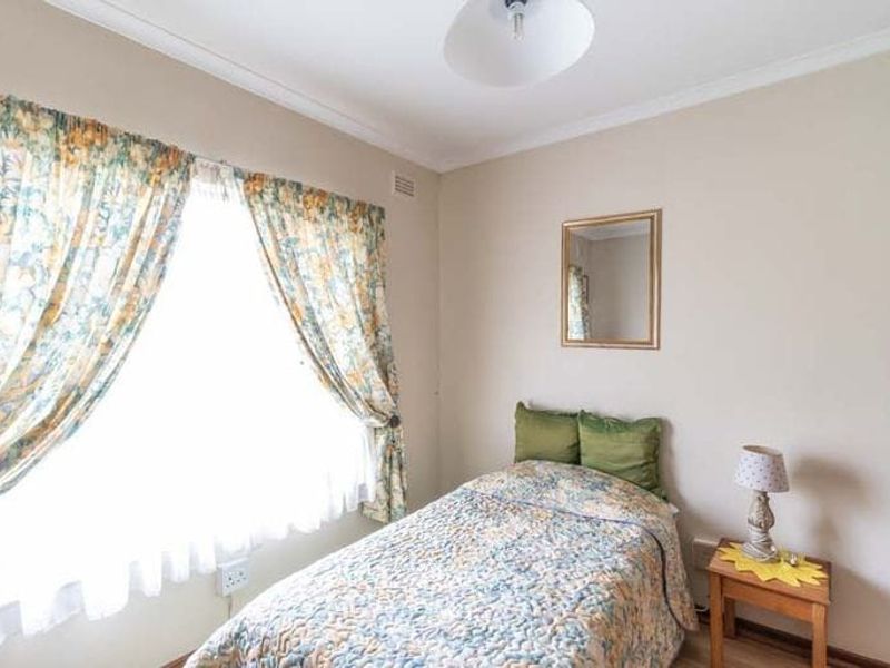A neutrally painted bedroom featuring coving and a large window with natural light.