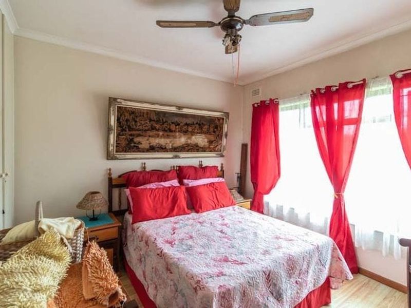 A bedroom featuring built-in cupboards, a ceiling fan, and laminate flooring, offering a functional space with neutral wall finishes.