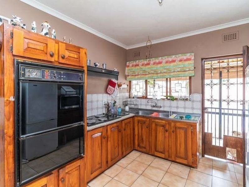 A functional kitchen featuring solid wood cabinetry, a built-in double oven, electric hob, and direct access to an exterior security gate.