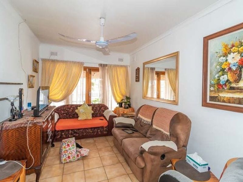 A comfortable living room featuring tiled flooring, a ceiling fan, and access to the outdoors through a sliding glass door.