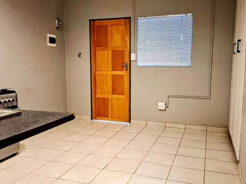 An empty kitchen area featuring tiled flooring, a built-in countertop, and exposed electrical conduit, offering a blank canvas for renovation.