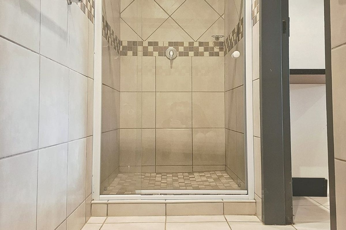 A clean bathroom featuring a glass-enclosed shower with neutral wall and floor tiling and a fitted towel rail.