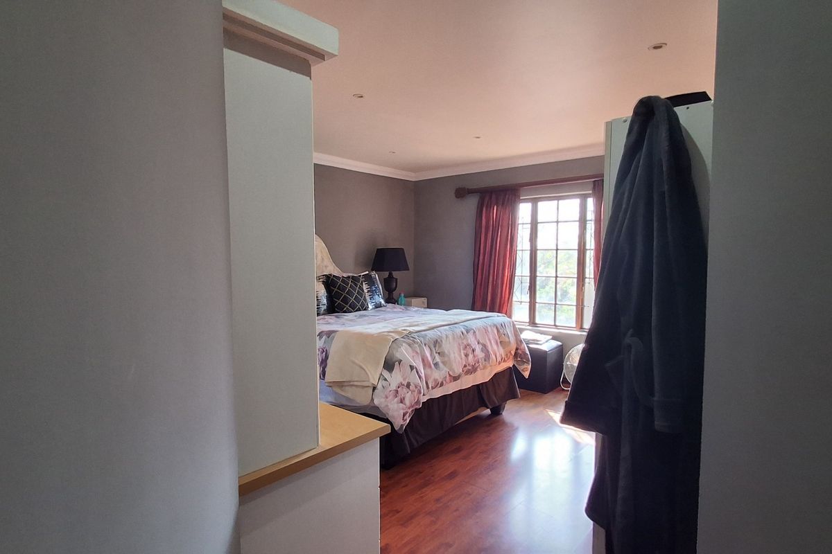 A bedroom featuring laminate flooring, recessed downlighting, and coving, viewed from an adjacent hallway or entryway.