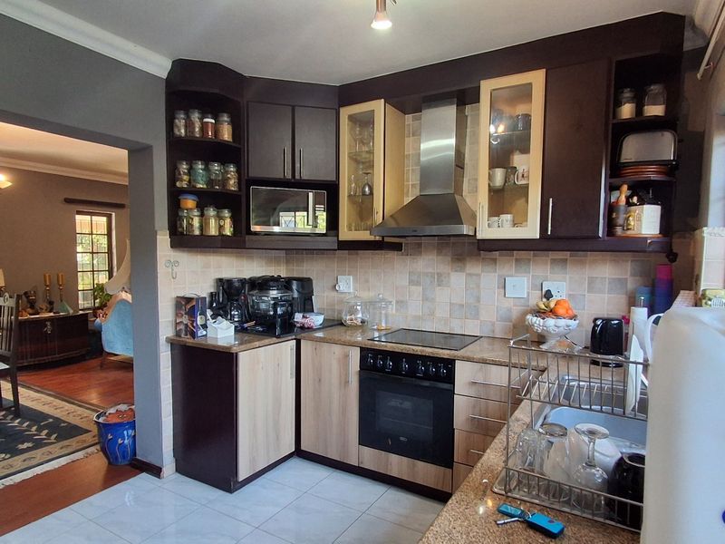 A functional kitchen featuring dark and light wood cabinetry, granite countertops, a built-in oven, and a stainless steel extractor fan, with an adjacent dining area.