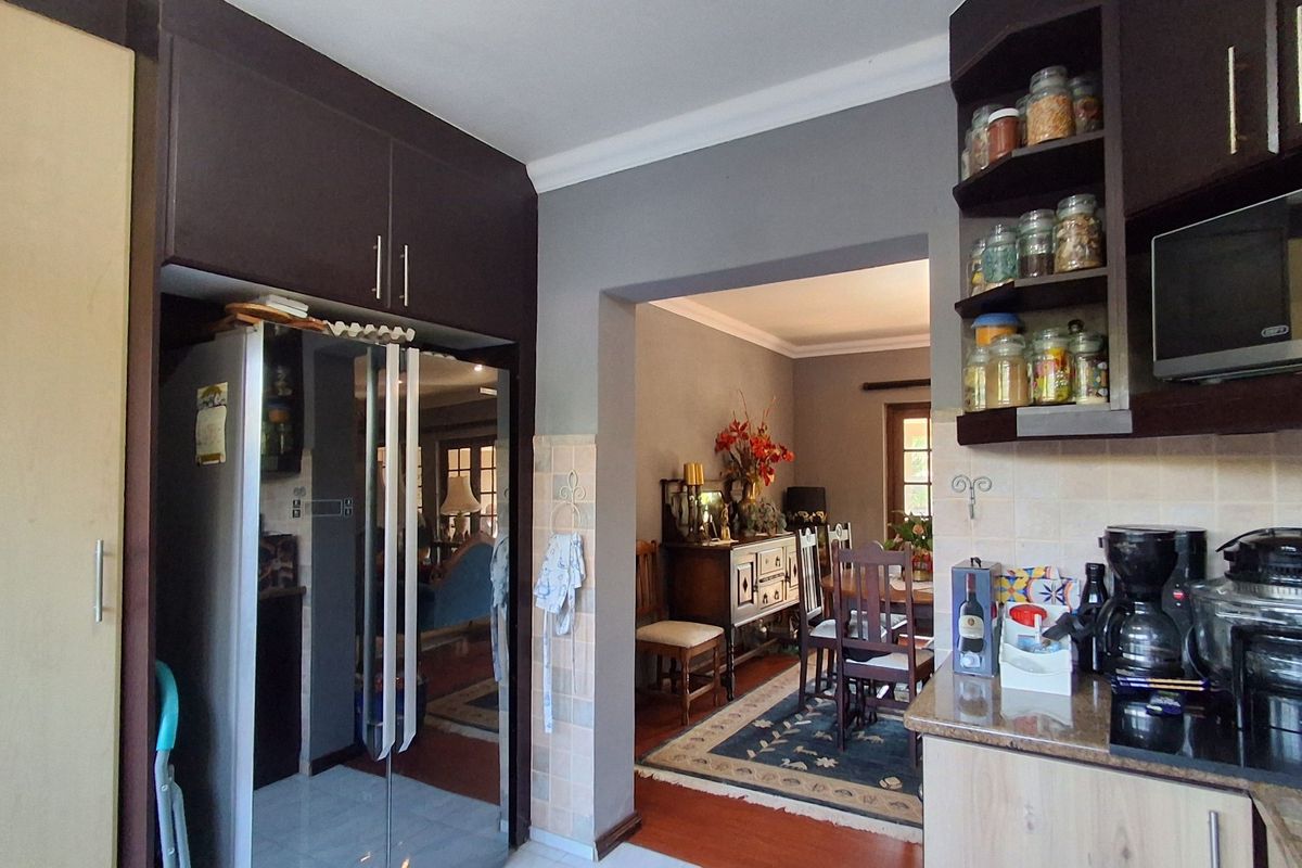 A functional kitchen featuring dark wood cabinetry, granite countertops, and a tiled backsplash, with an open-plan flow into the adjacent dining area.