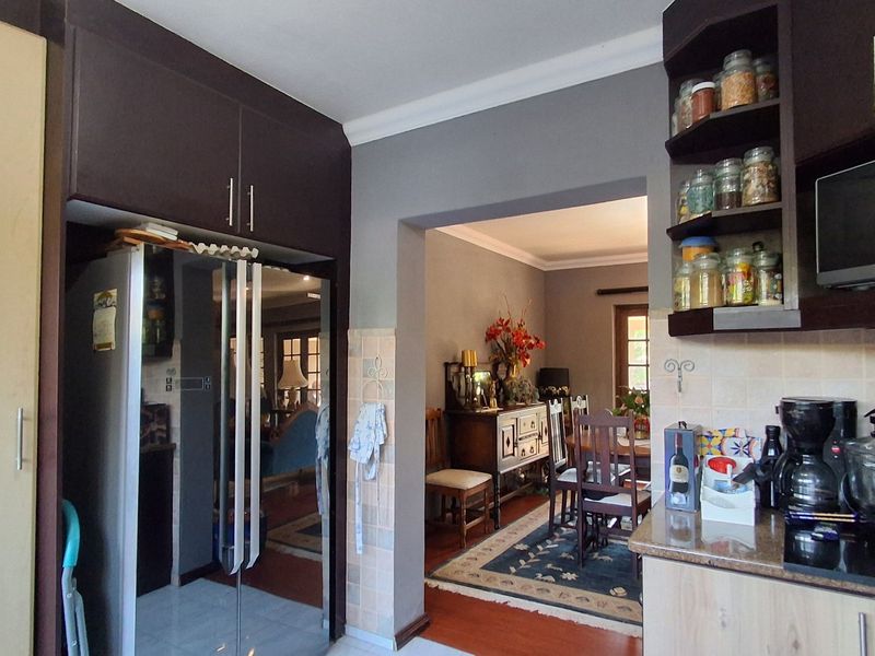 A functional kitchen featuring dark wood cabinetry, granite countertops, and a tiled backsplash, with an open-plan flow into the adjacent dining area.