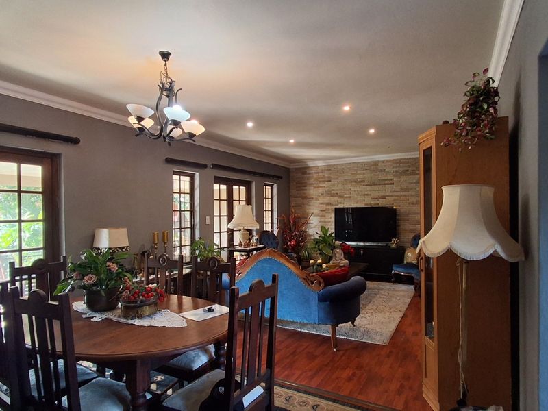 Spacious open-plan living and dining area featuring hardwood flooring, a stone feature wall, and elegant french doors leading to the exterior.