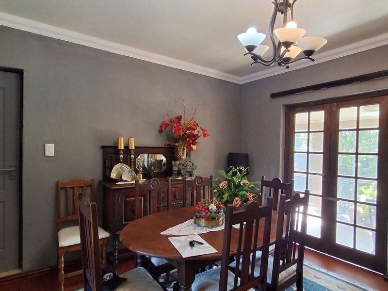 A well-maintained dining room featuring crown molding, a classic chandelier, and double french doors providing access to the outdoor area.