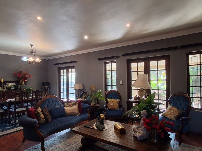 Spacious open-plan living and dining area featuring timber flooring, recessed lighting, and multiple sets of french doors providing natural light and garden access.