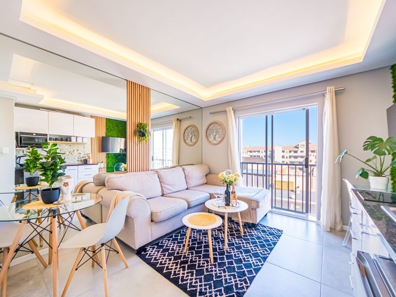 Modern open-plan living area featuring recessed ceiling lighting, mirrored wall accents, slatted timber detailing, and direct access to a private balcony.
