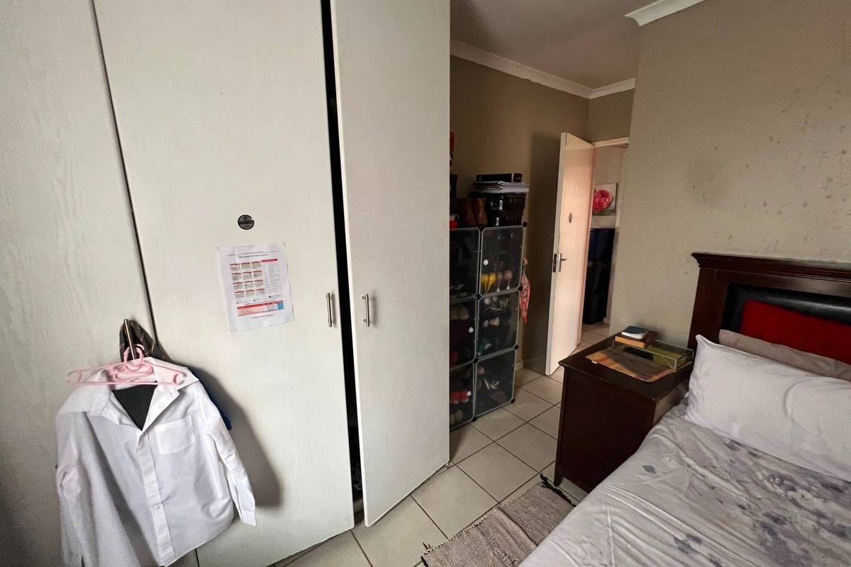A bedroom featuring built-in cupboards and tiled flooring, requiring cosmetic updates to the wall finishes to improve the overall aesthetic.