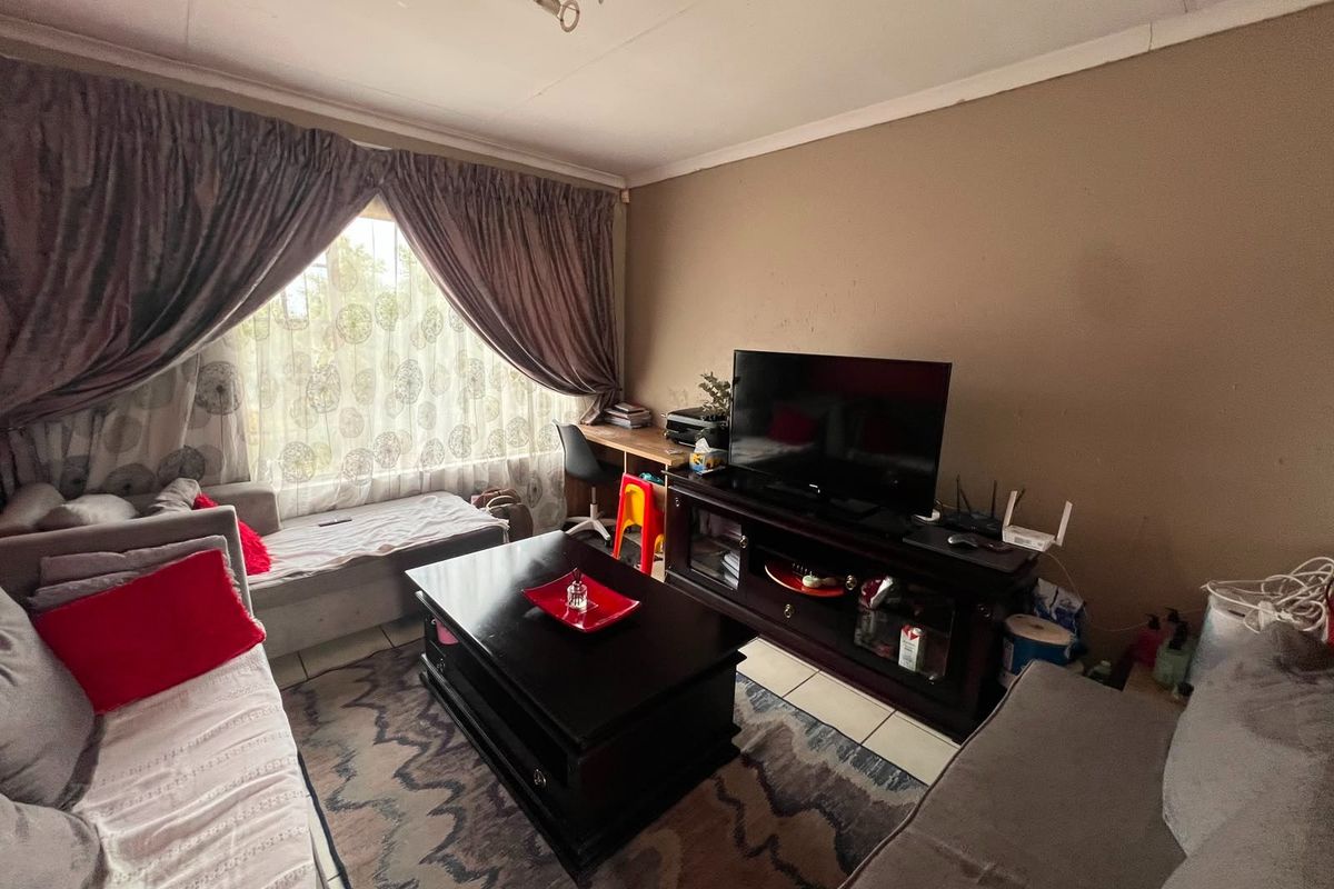 A living room featuring tiled flooring and neutral wall tones, offering a functional space that would benefit from cosmetic updates and fresh paint.