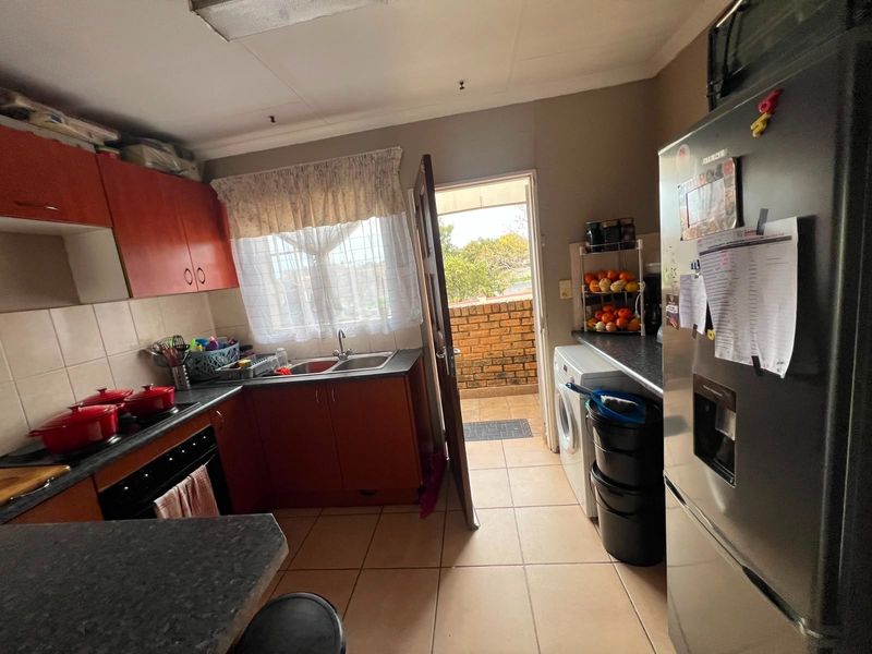 Functional kitchen featuring built-in cabinetry, laminate countertops, a double bowl sink, and direct access to an outdoor balcony area.