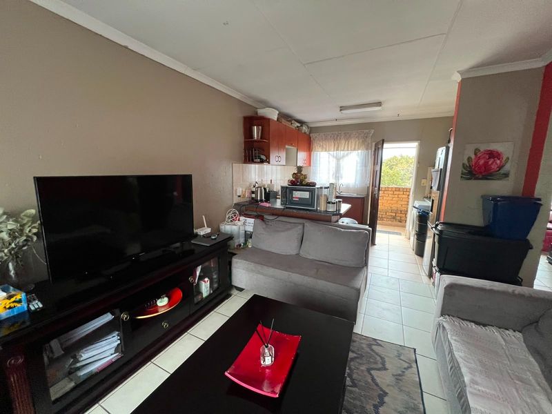 Open-plan living area featuring tiled flooring and a functional kitchen space with direct access to an outdoor balcony.