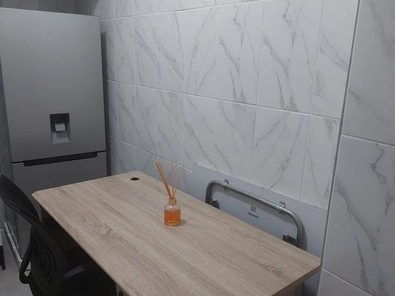 A compact scullery or utility area featuring modern marble-look wall tiling and built-in overhead storage cabinetry.