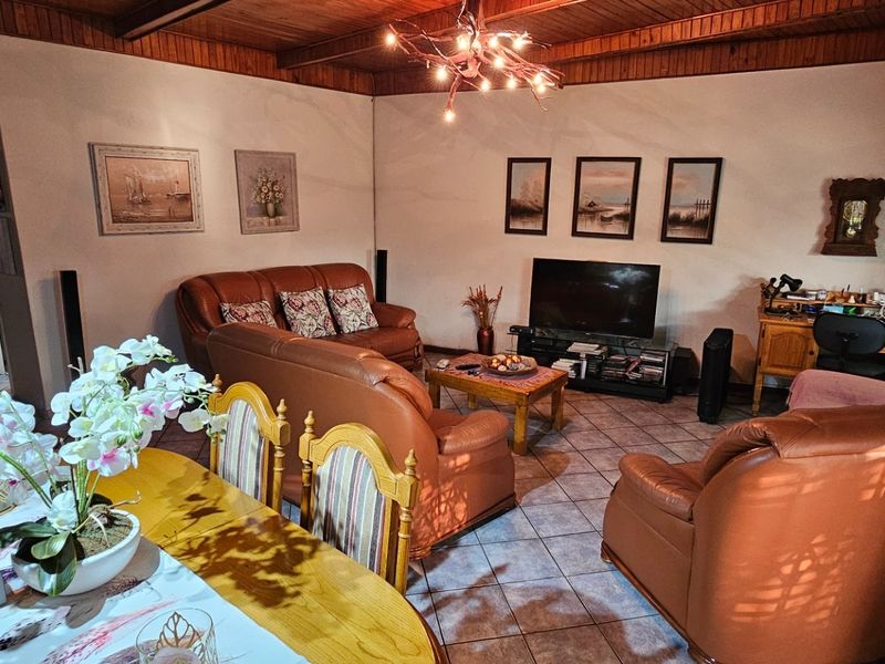 Open plan living and dining area featuring tiled flooring and a timber tongue and groove ceiling with exposed beams.
