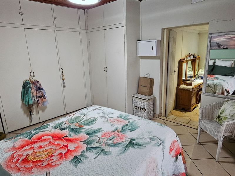 A bedroom featuring built-in cupboards, tiled flooring, and a timber ceiling, offering a functional space with potential for cosmetic updates.
