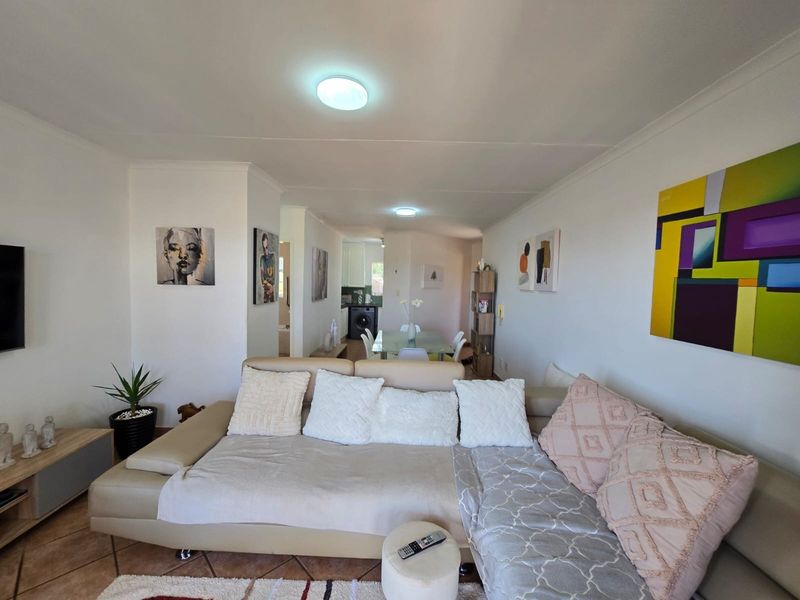 An open-plan living and dining area featuring tiled flooring and neutral walls, providing a functional layout that flows into the kitchen space.