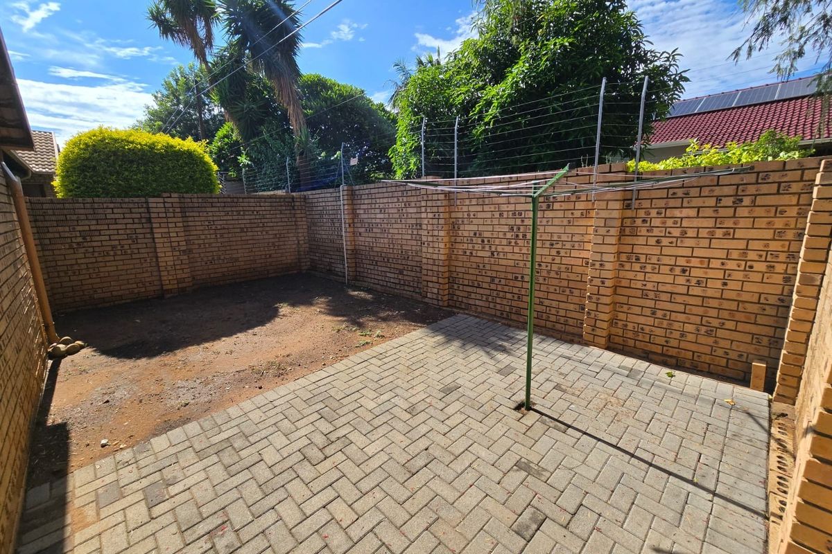 A private rear courtyard featuring a paved patio area, brick boundary walls with electric fencing, and a dedicated space for a clothesline.