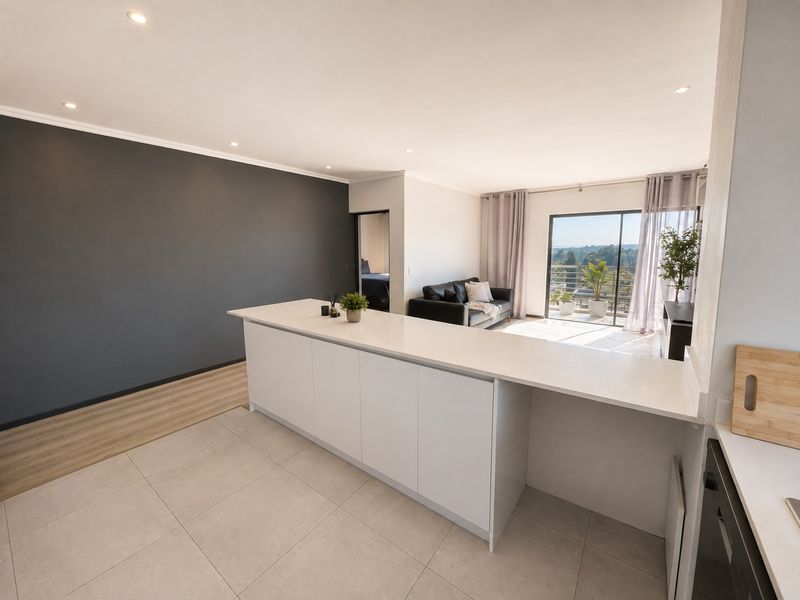 Modern open-plan living area featuring a sleek kitchen island, tiled and laminate flooring, and seamless access to a balcony with scenic views.