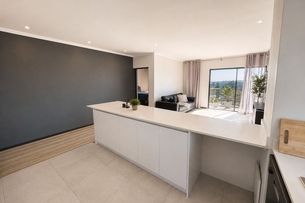 Modern open-plan living area featuring a sleek kitchen island, tiled and laminate flooring, and seamless access to a balcony with scenic views.