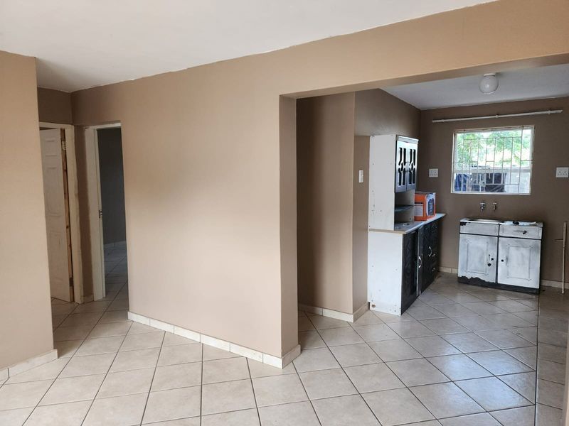 Open plan living area featuring tiled flooring and a basic kitchen corner with built-in cabinetry and a sink.