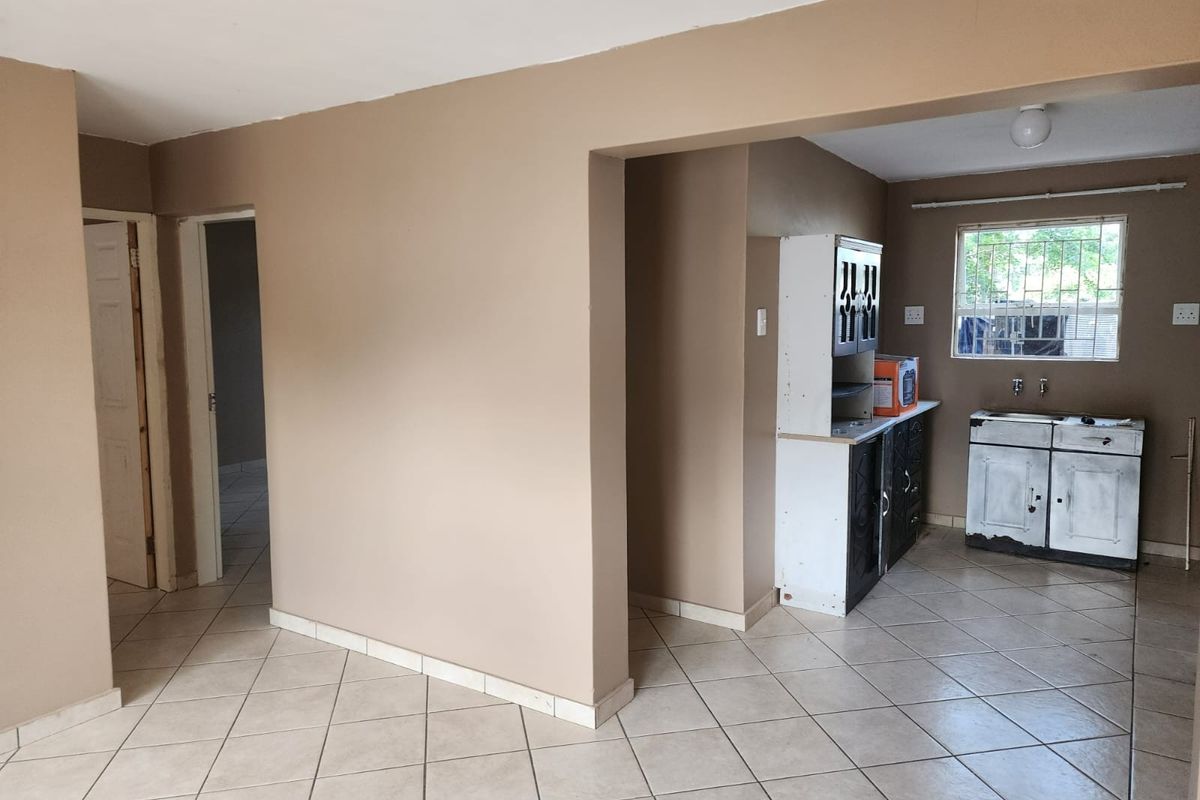 Open plan living area featuring tiled flooring and a basic kitchen corner with built-in cabinetry and a sink.