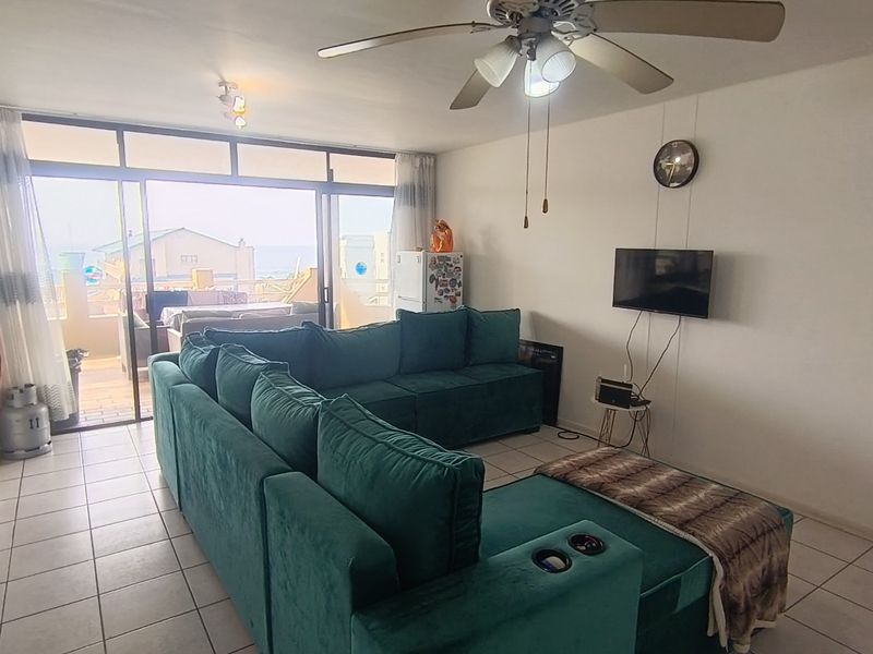 Spacious living room featuring tiled flooring, a ceiling fan, and large sliding glass doors providing access to an outdoor balcony area.