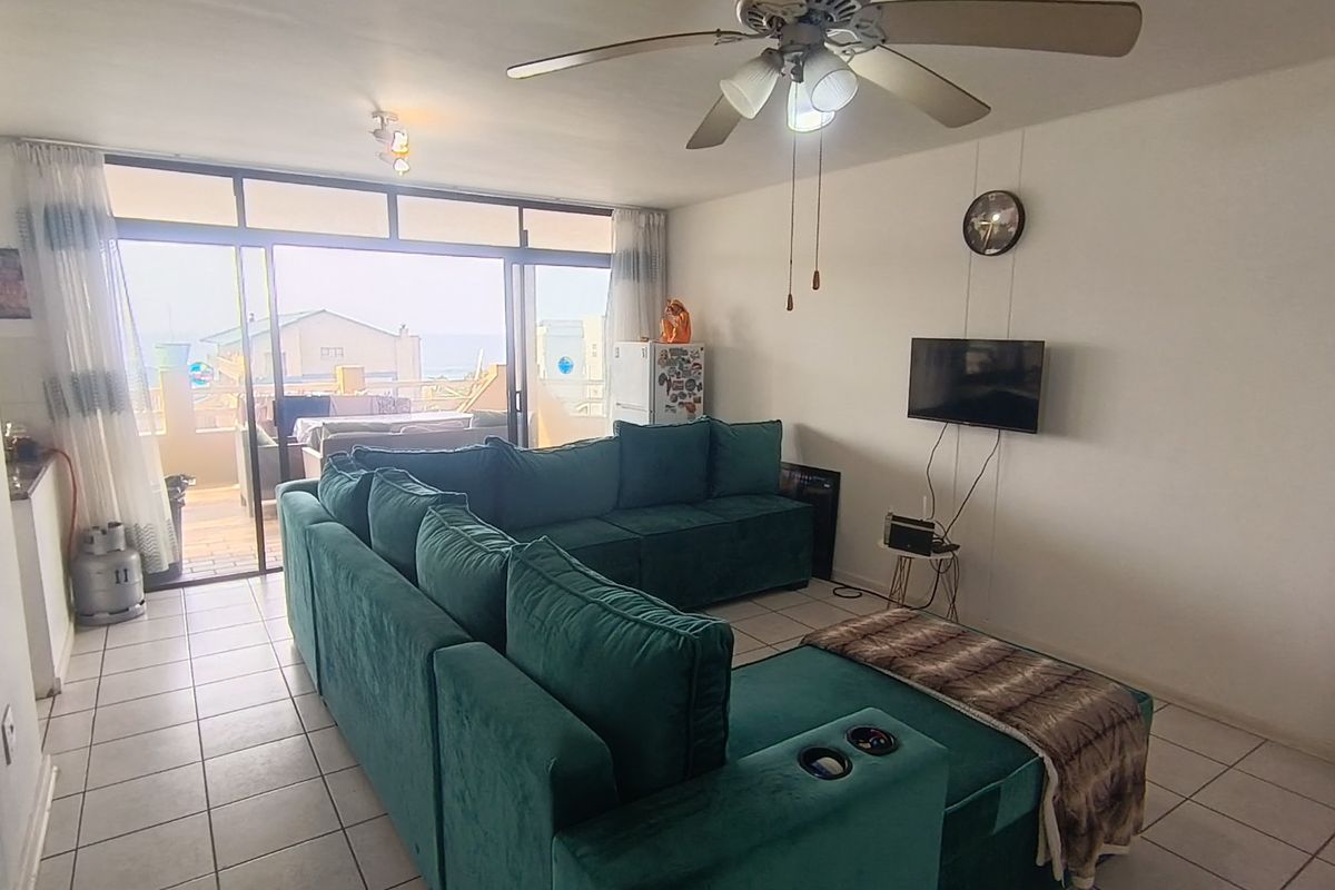 Spacious living room featuring tiled flooring, a ceiling fan, and large sliding glass doors providing access to an outdoor balcony area.