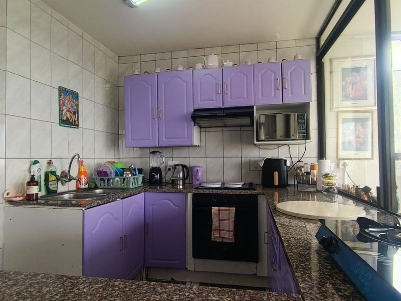 A functional kitchen featuring granite countertops, built-in cabinetry, an integrated oven, and a tiled backsplash, offering a practical layout for daily meal preparation.