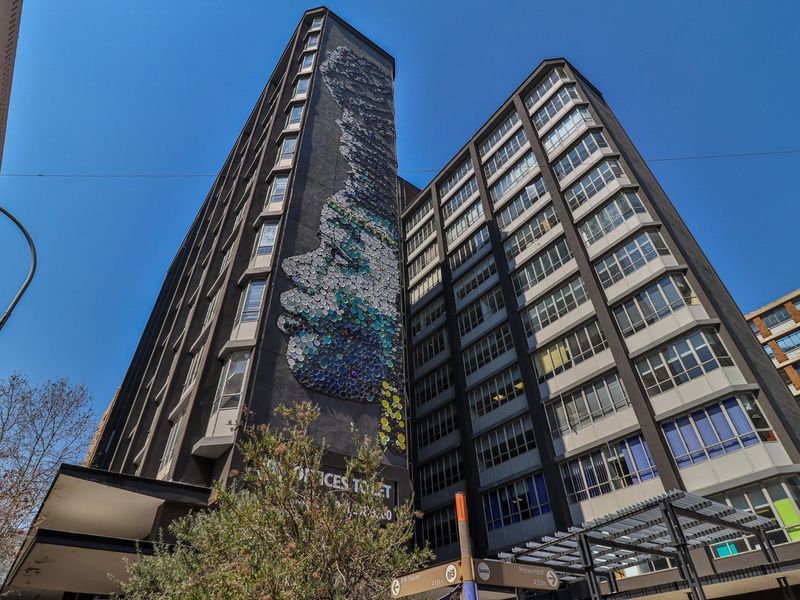 A low-angle view of a multi-story commercial building featuring a prominent artistic mural on the facade and extensive window glazing.