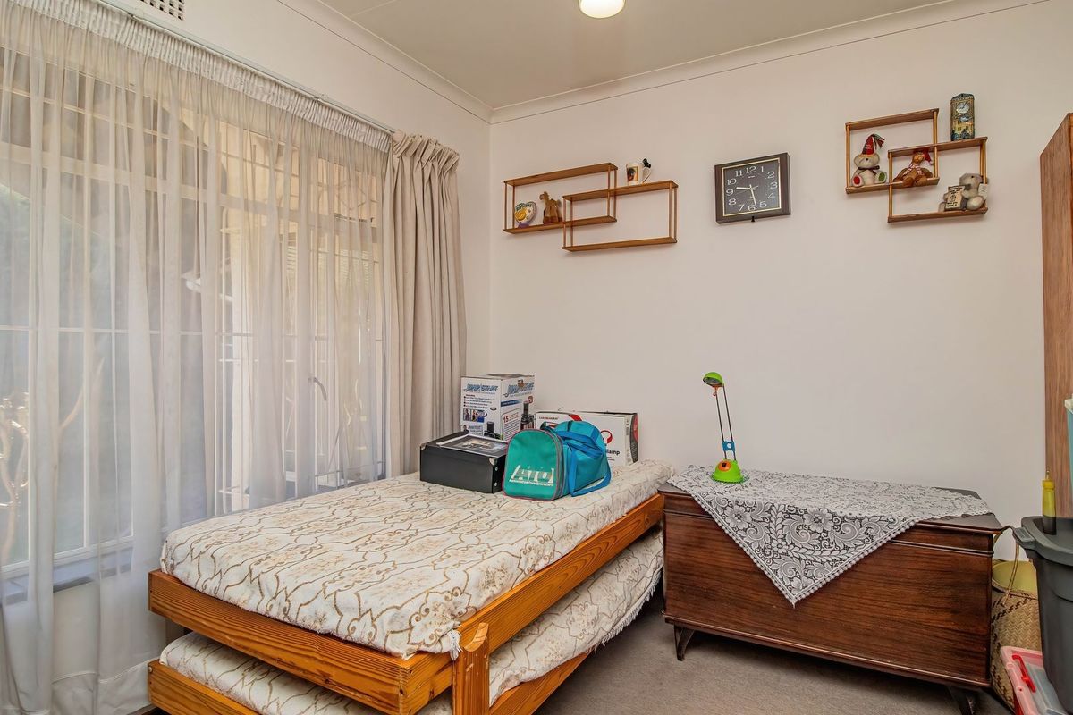 A functional bedroom featuring neutral walls, coving, and large windows with curtain tracks, providing a blank canvas for potential updates.