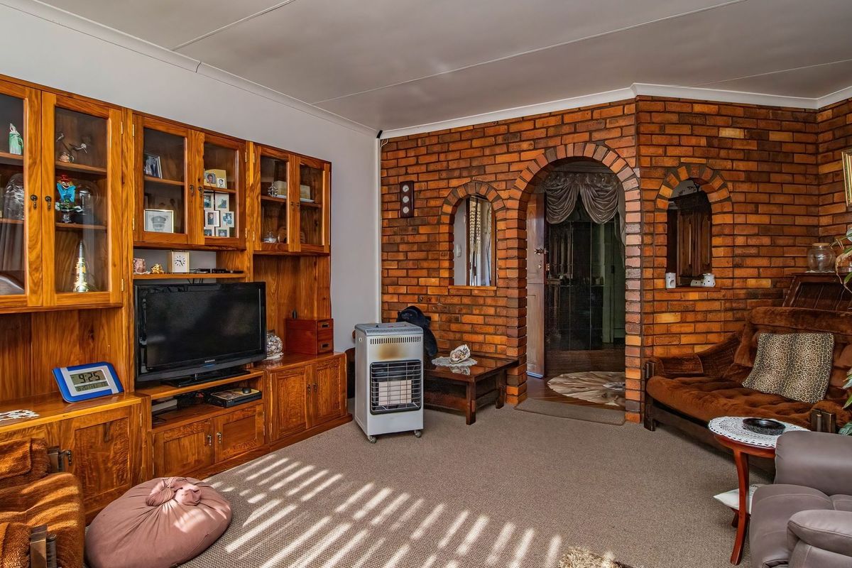 A living room featuring an exposed brick wall with arched openings and built-in wooden cabinetry, providing a traditional aesthetic.